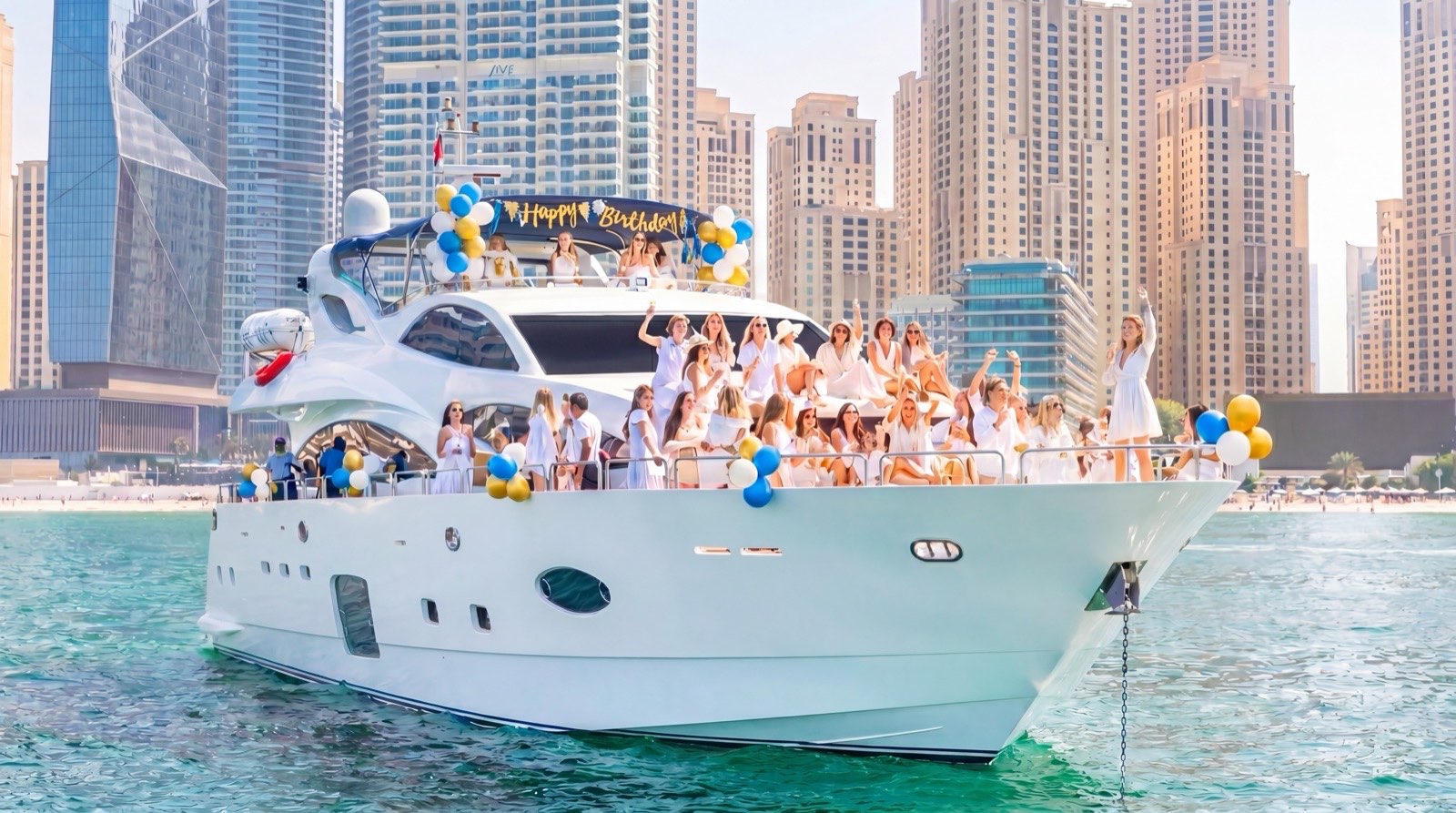 Large group celebrating on the flybridge and bow of a yacht near Dubai Marina