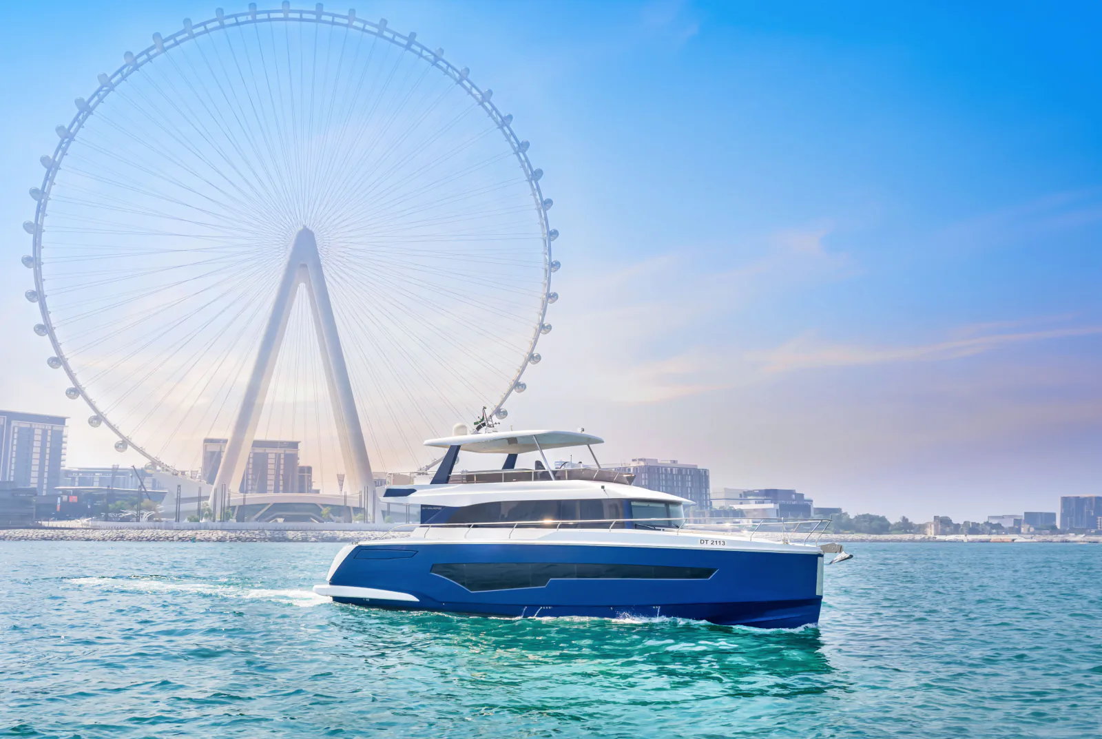 62 feet yacht rental Dubai: the opposite side of the blue yacht on open water with the observation wheel behind.