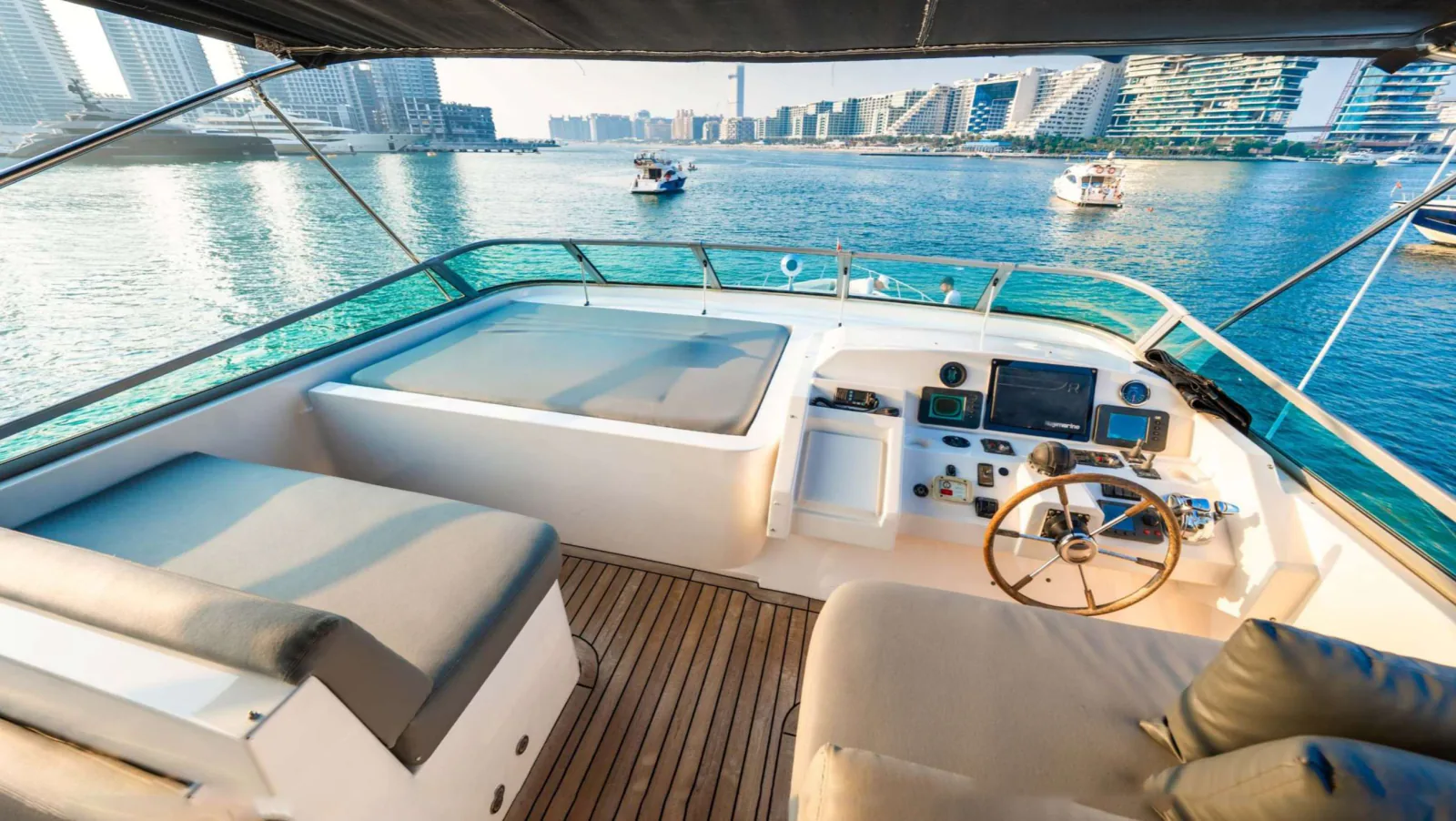 Majesty 77 yacht upper helm station with the wheel and instruments beside a cushioned lounger.