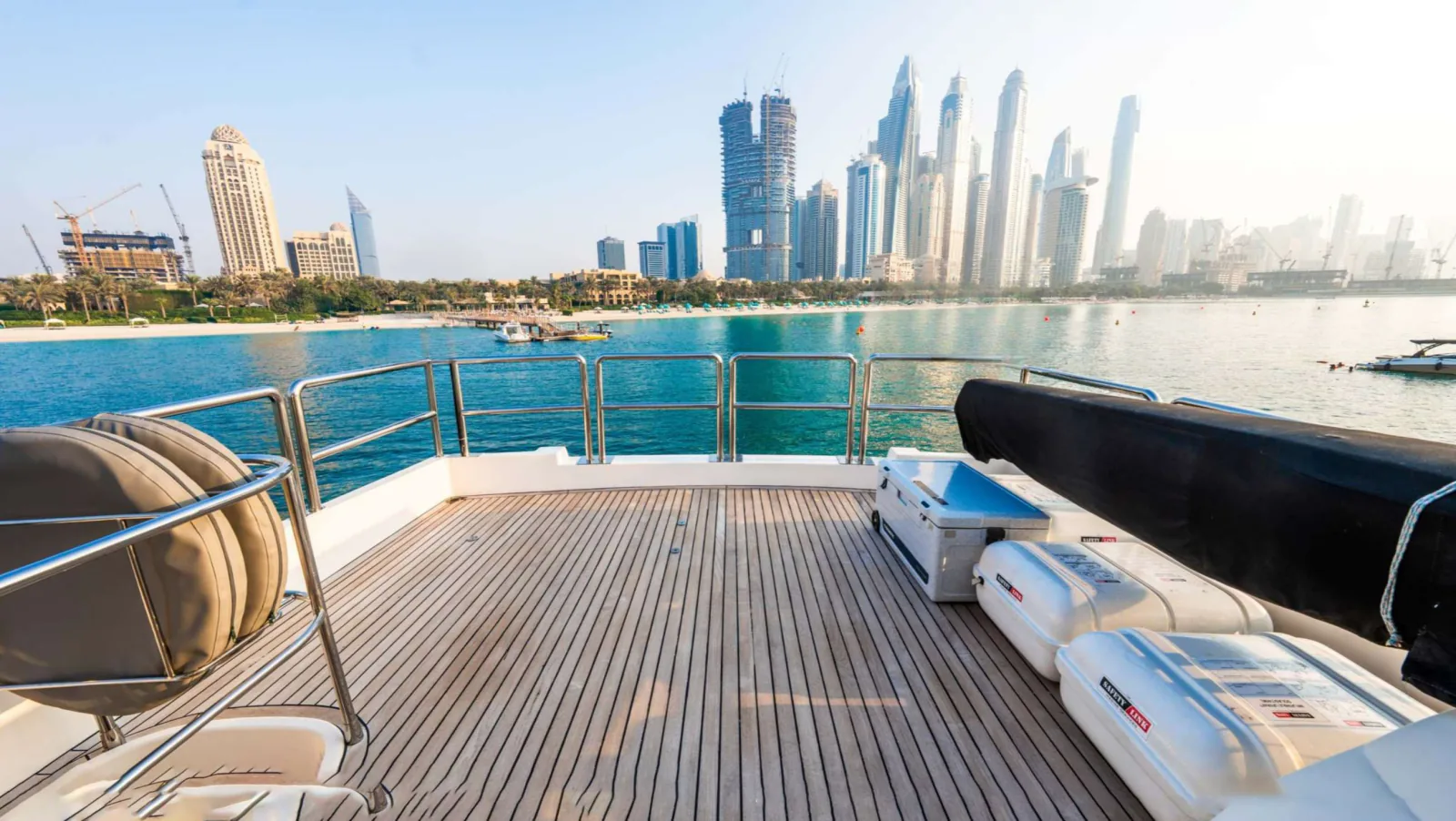 Majesty 77 yacht open teak deck with a city skyline and shoreline beyond the railing.