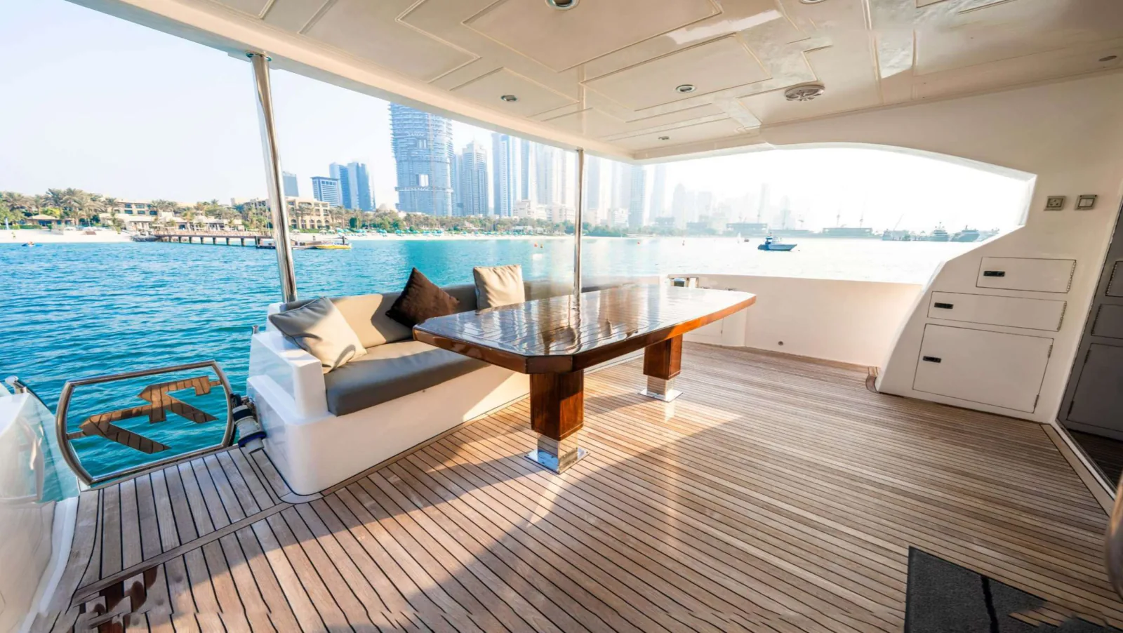 Majesty 77 yacht shaded aft deck with a dining table and bench seating.
