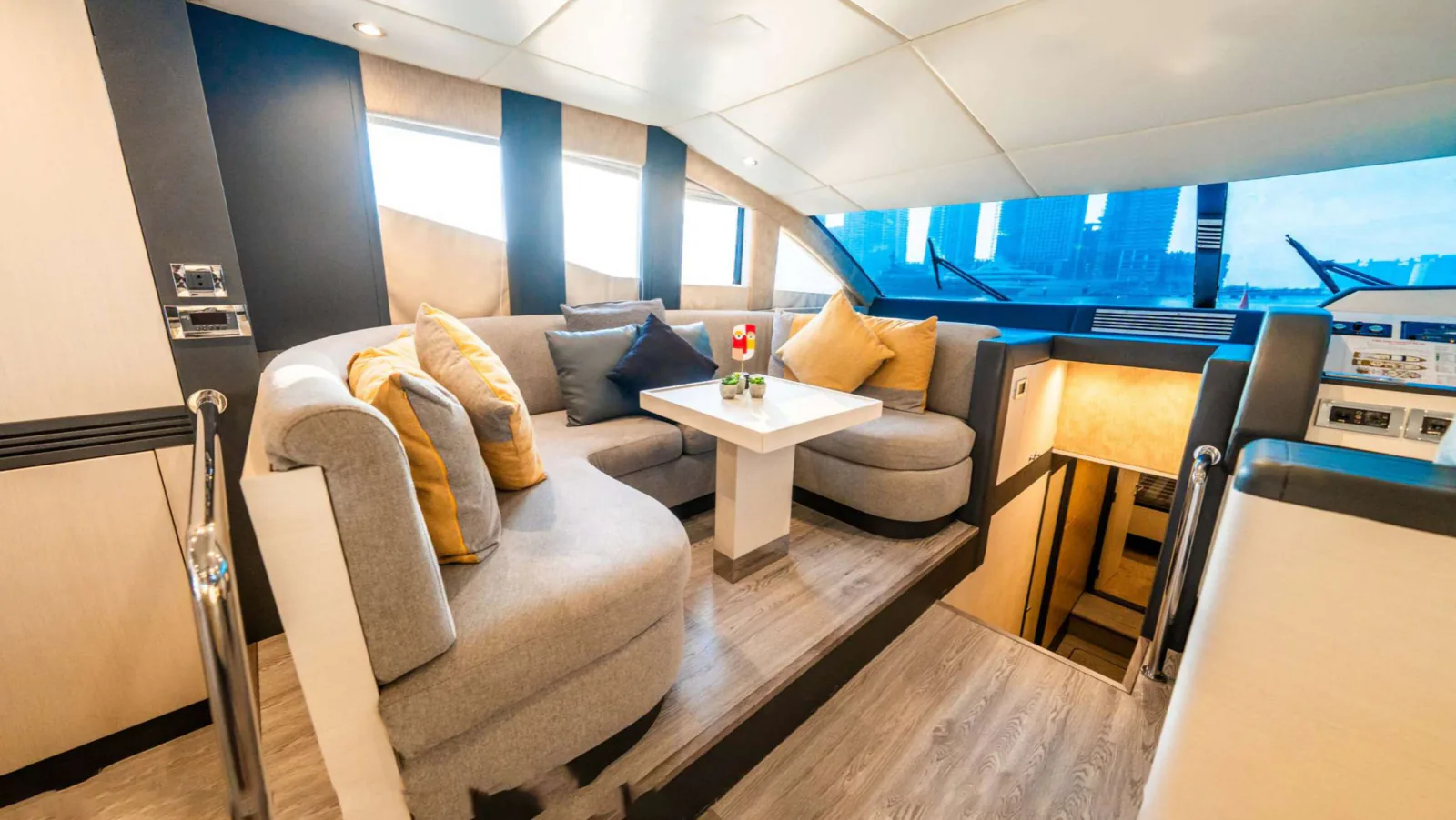 Majesty 77 yacht forward saloon with a curved sofa and a low table.