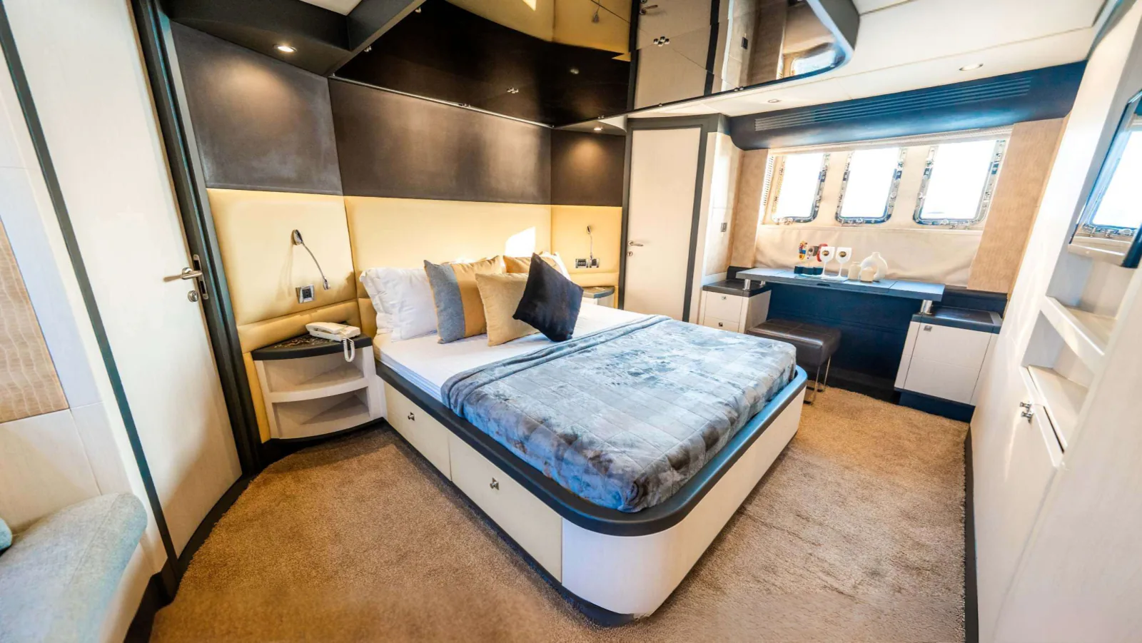 Majesty 77 yacht cabin with a double bed, a desk and portholes.