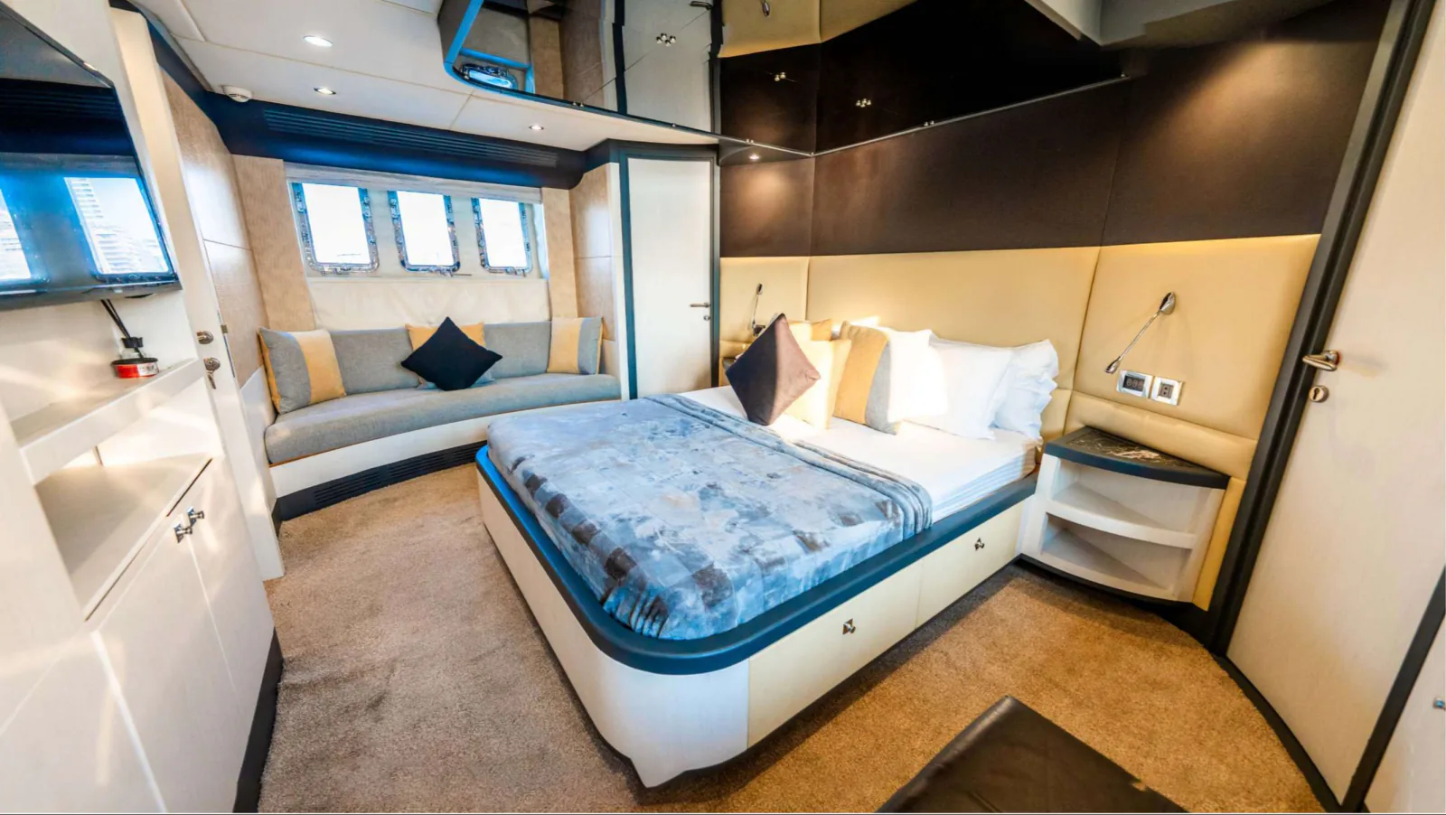 Majesty 77 yacht cabin with a double bed, a side settee and portholes.