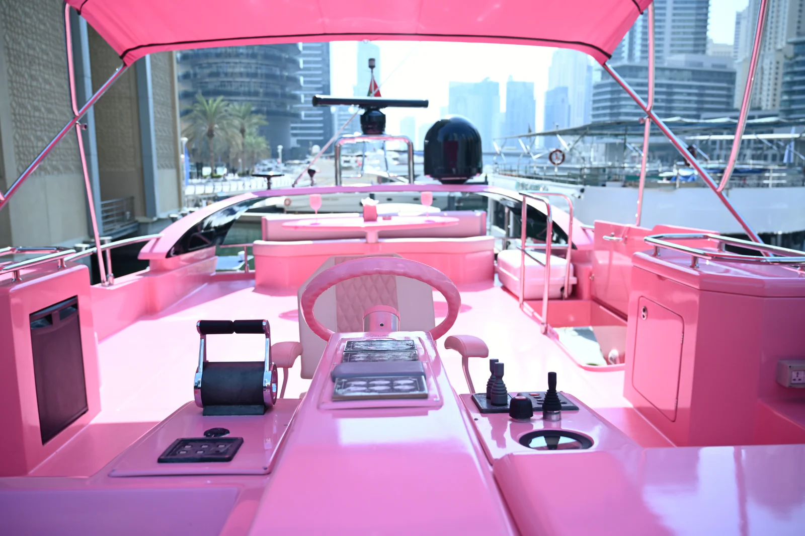 Pink yacht rental Dubai flybridge with pink helm and guest seating