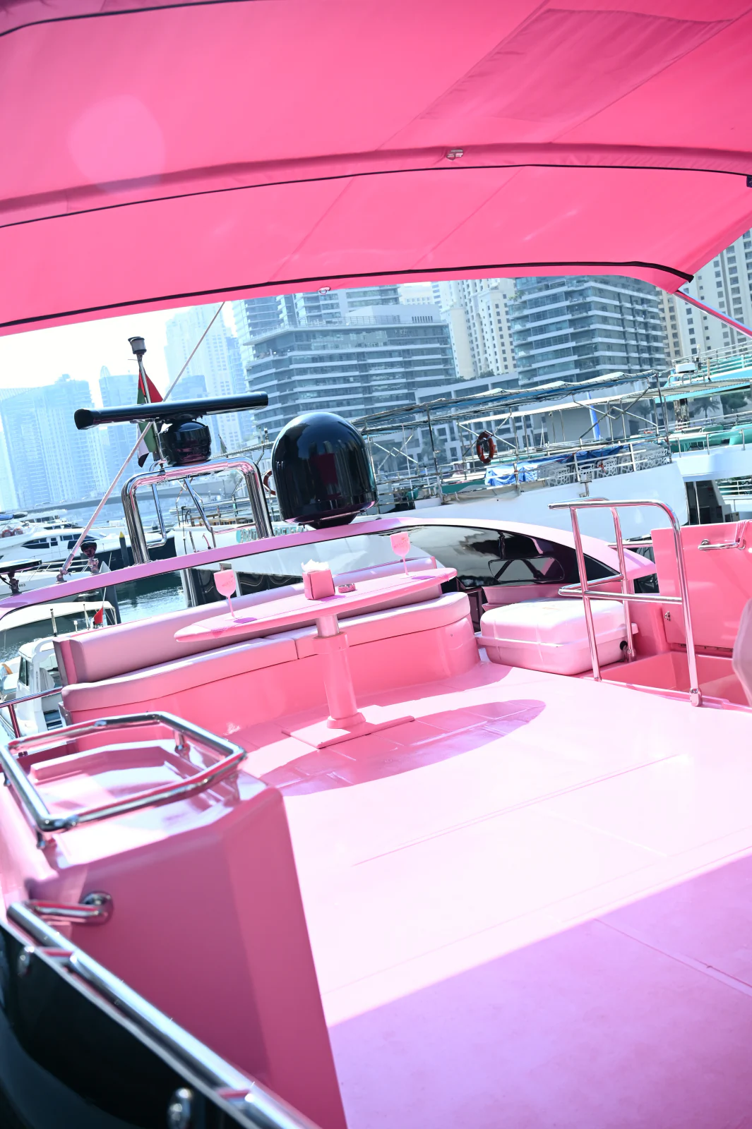 Pink yacht rental Dubai with flybridge lounge seating and table