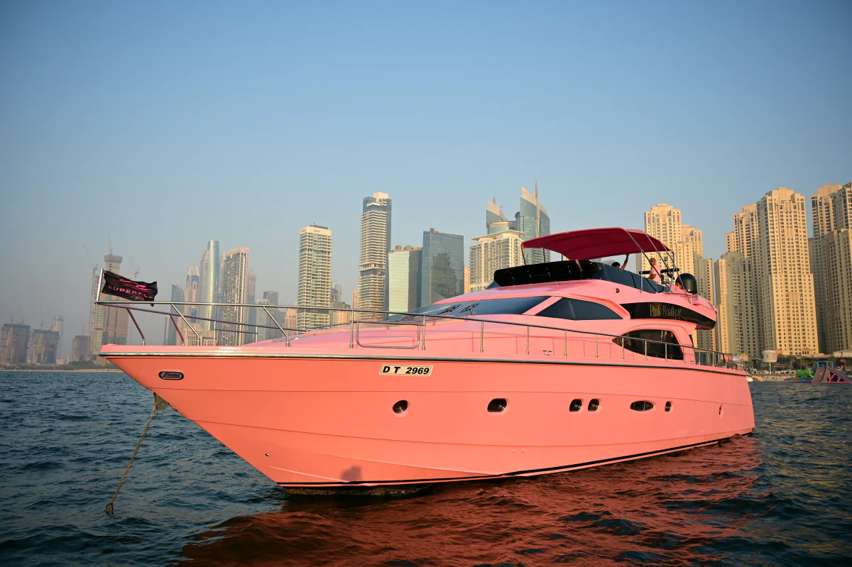 Pink yacht rental Dubai showing the full 64 feet Pink Boatique exterior beside the marina skyline